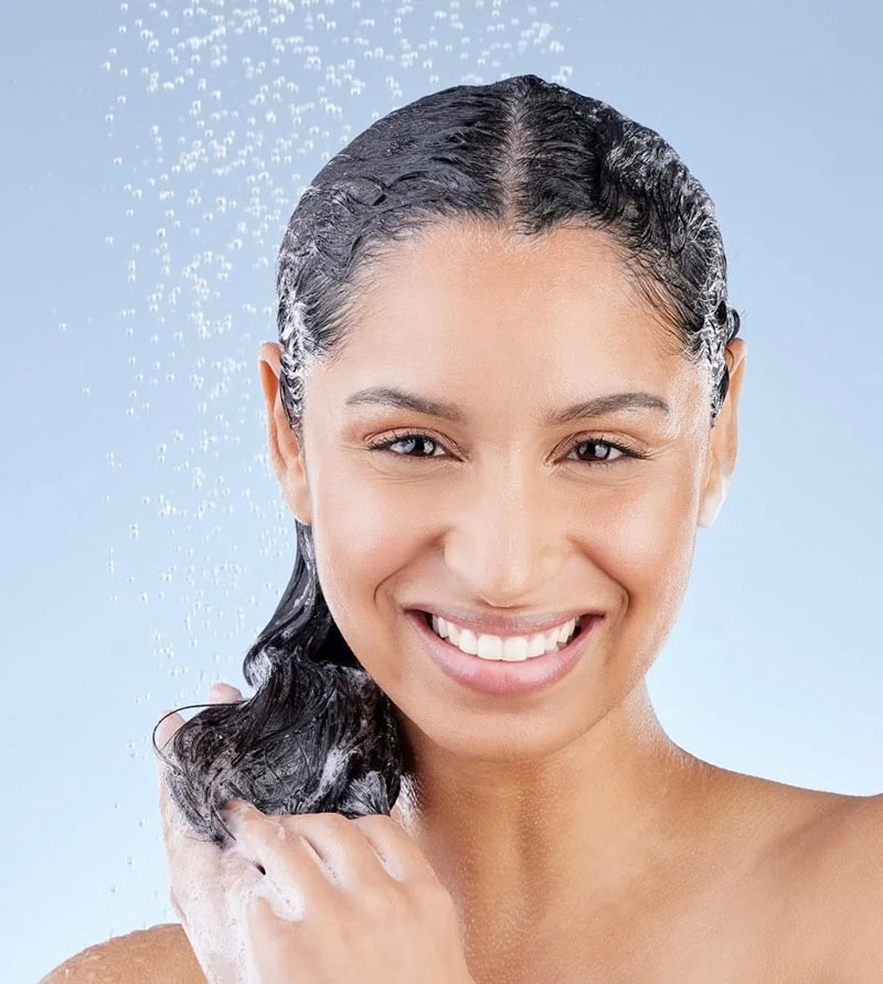 Woman lathering hair in shower, depicting common mistakes while co-washing like doing it once