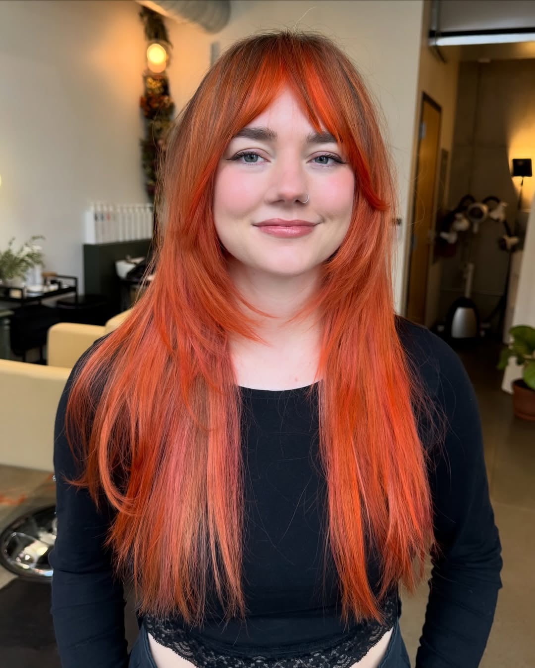 Long vibrant copper hair cut into feathered face-framing bangs with long cascading layers