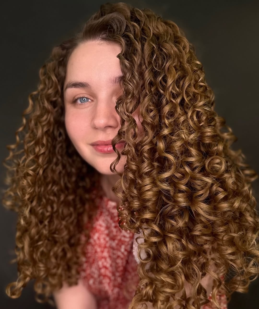 voluminous light brown curly perm framing the face