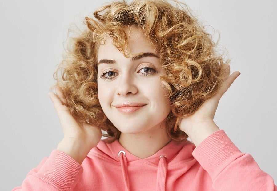 caramel blonde curly shag bob with soft curls and a side-swept fringe