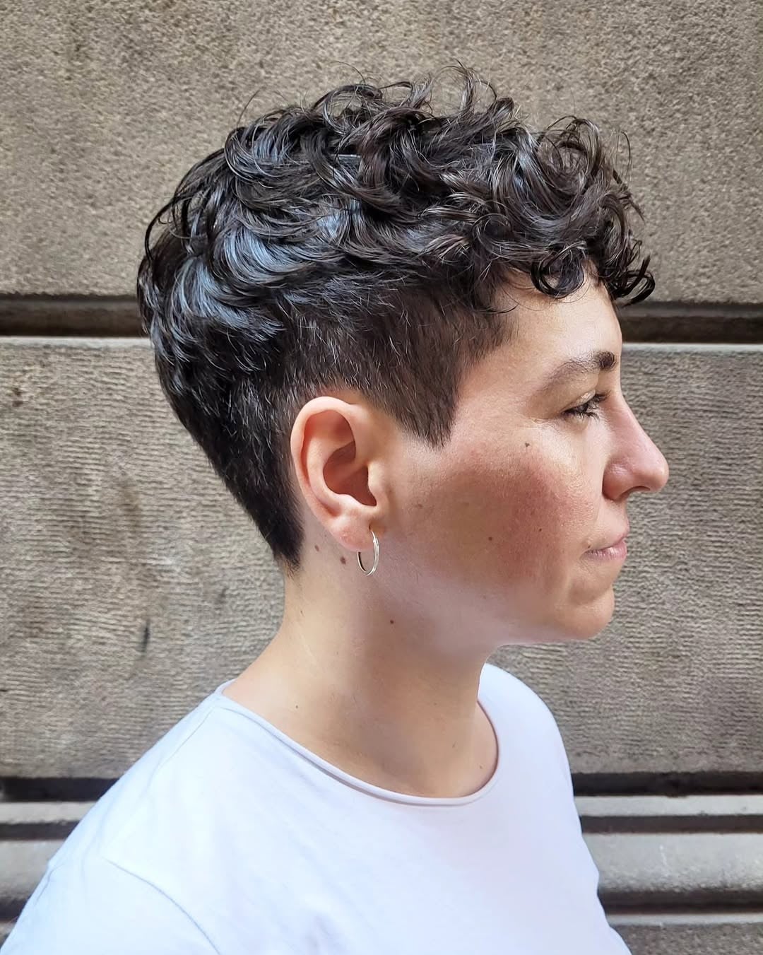 Dark curly pixie with defined curls on top and closely cropped sides and back