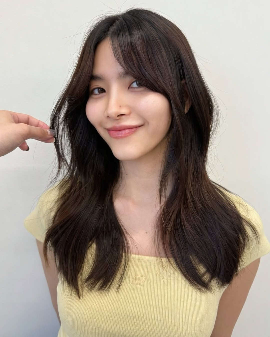 Long dark layered hair and soft center parted curtain bangs for heart shaped face