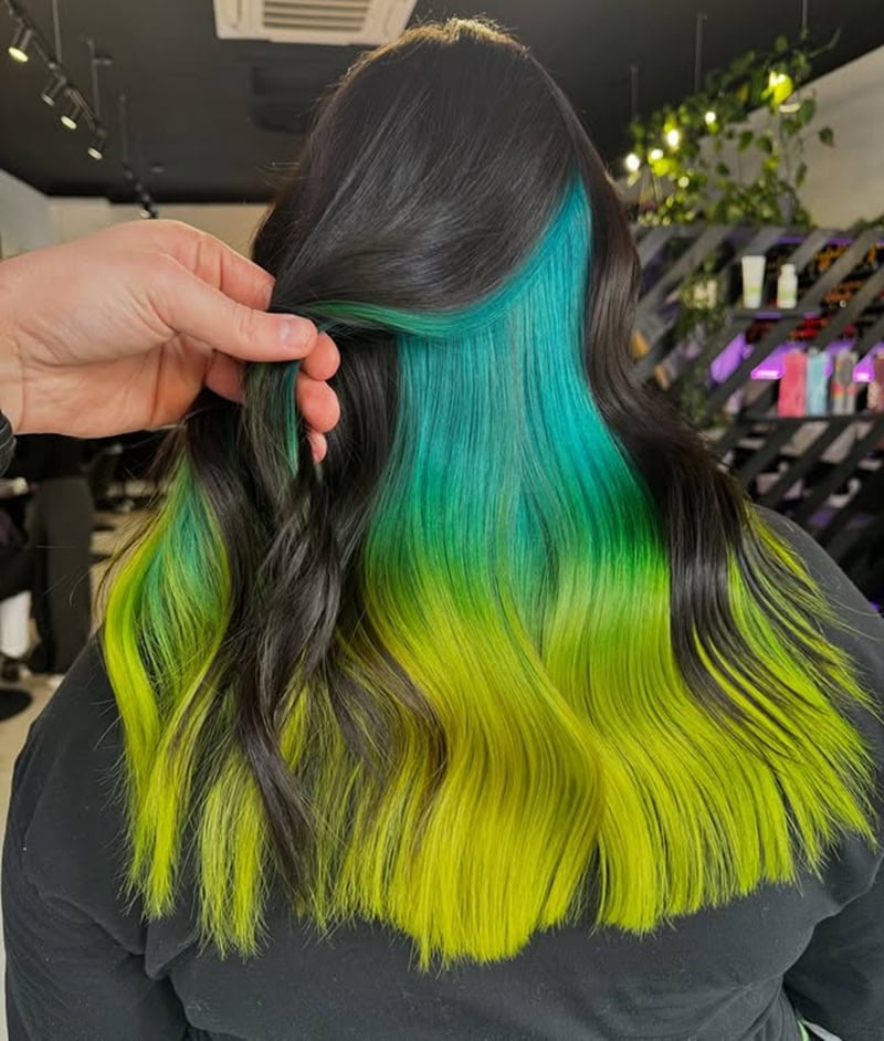 Black hair lifted to reveal a hidden blue and chartreuse green underlayer