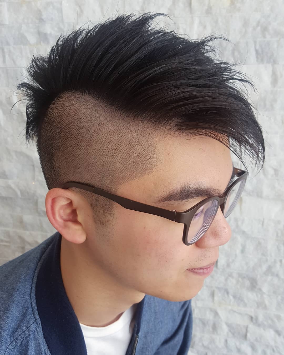Asian disconnected undercut haircut featuring high shaved sides and spiky black hair