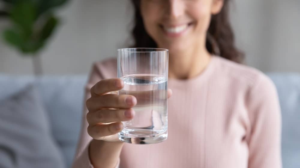 glass with mineral clean water in female hands