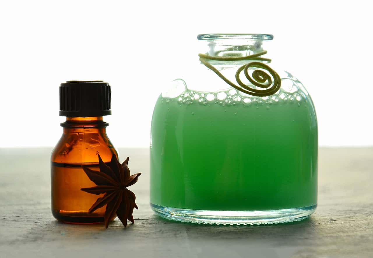 small bottle of hair oil with jar of green shampoo