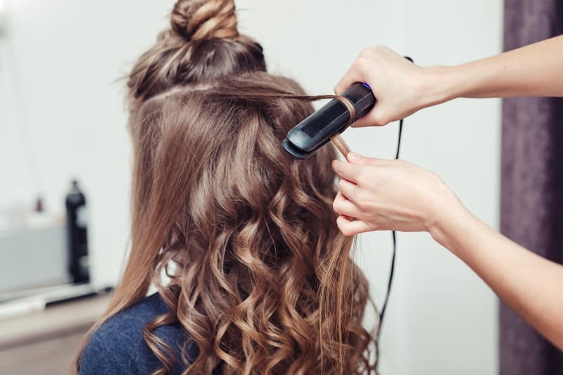 hairdresser working on creating curls using flat iron