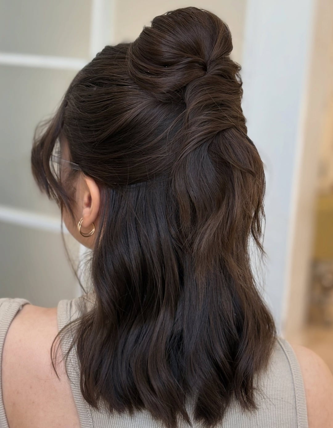 Woman featuring a half-up twisted top knot formal hairstyle for medium hair