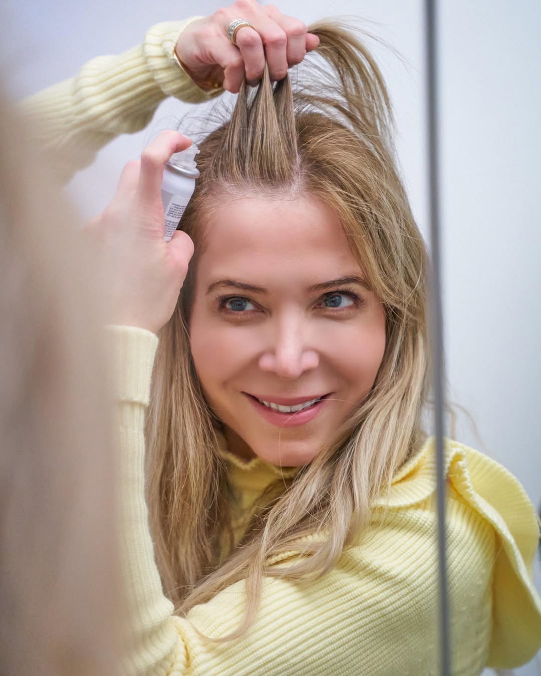 woman using root concealer spray to hide gray hairline