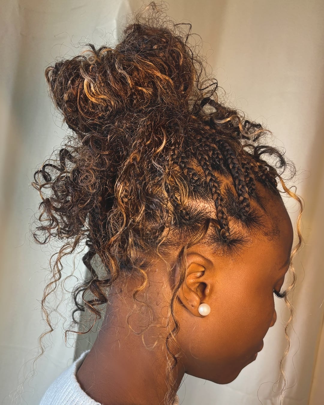 High messy boho braid bun with golden highlights as a vacation hairstyle for black women