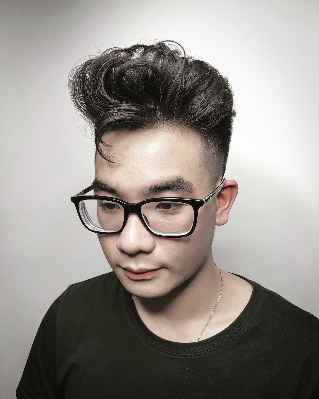 Man with glasses wearing a high-volume messy pompadour fade haircut