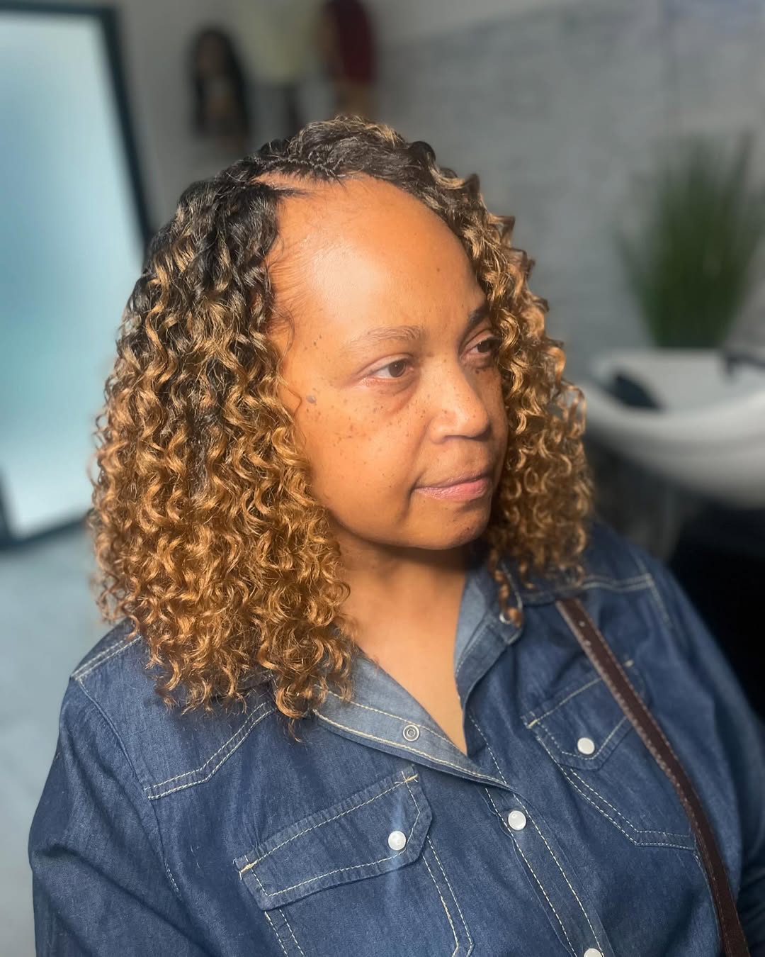 Shoulder-length curly bob crochet hairstyle with tight ringlets and honey blonde ombre color