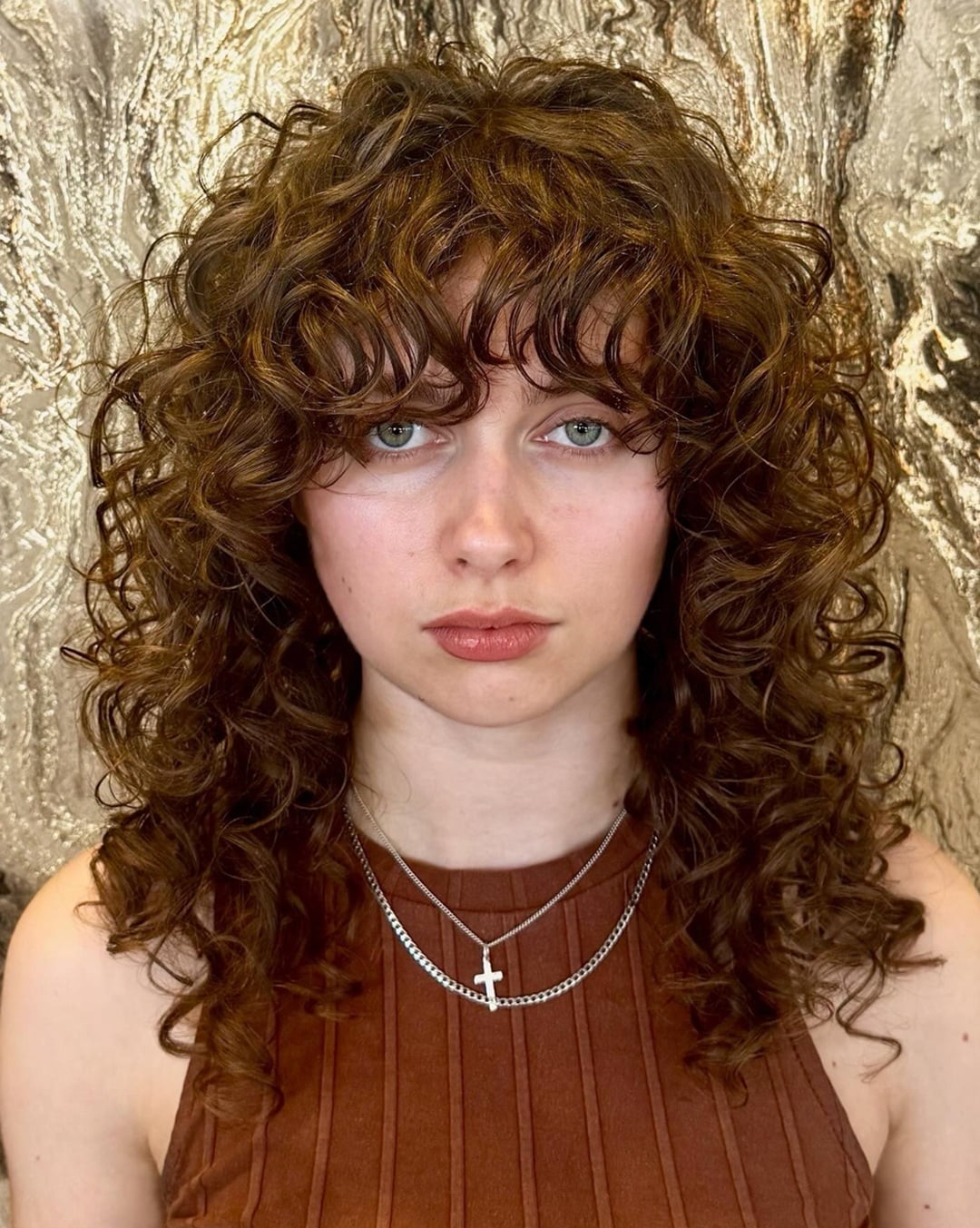 medium length light brown curly shag haircut with full curly bangs