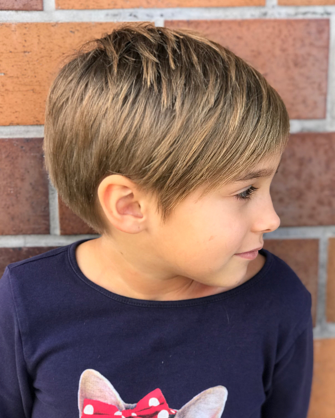 little girl with light brown pixie cut with short side bangs