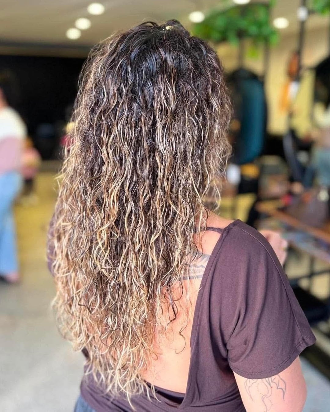 Back view of long permed hair featuring tight cascading waves and long layered length