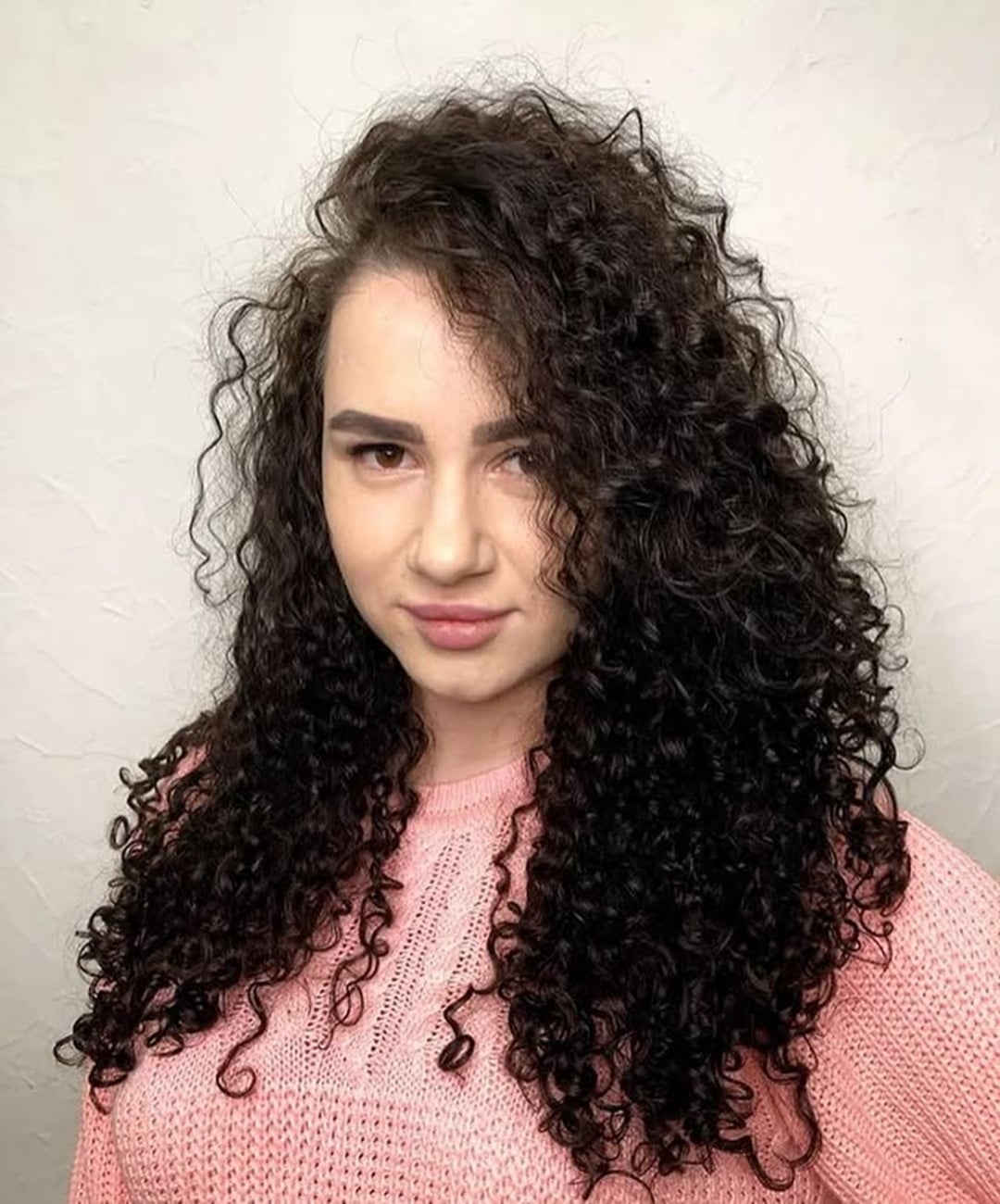 long dark brown curly perm hairstyle featuring tight spiral ringlets and a deep side part