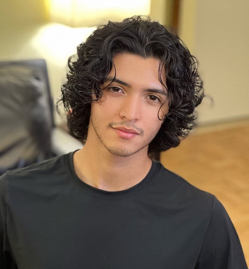 Young boy with dark, glossy shoulder-length loose waves