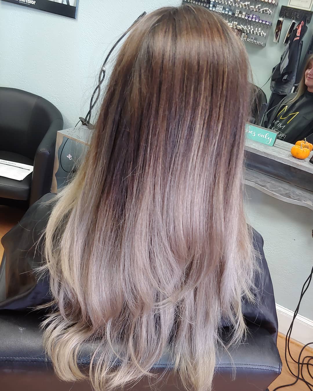 Long straight layered hair featuring a cool mushroom blonde ombre with dark ash roots