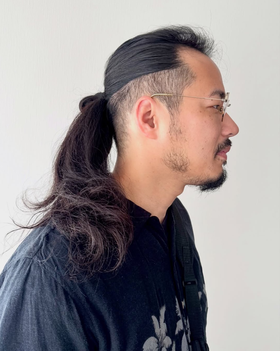 Asian man wearing a long hair ponytail with a high-shaved undercut