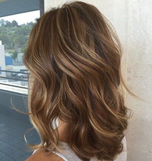 Back view of long wavy brown hair featuring delicate subtle blonde highlights for dimensional tone