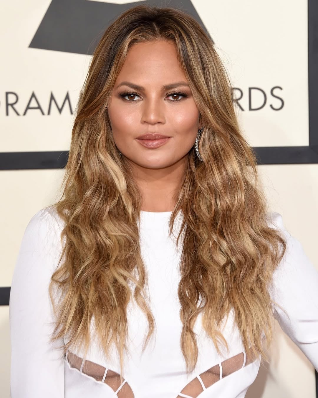 long wavy honey blonde and brown highlighted hair with a center part on a woman with a round face