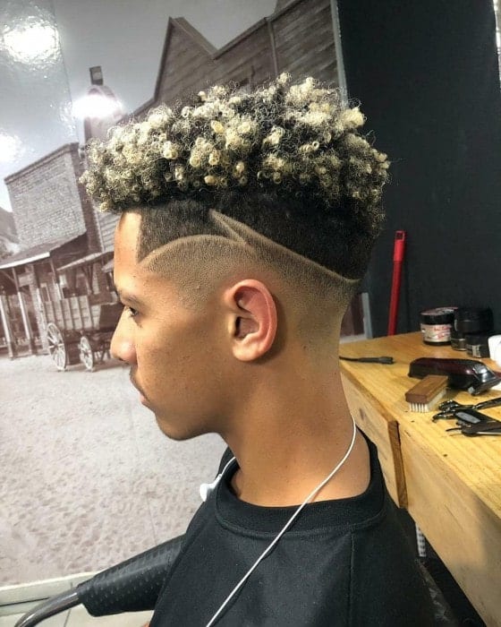 Highlighted curly hair with a fade and low styling