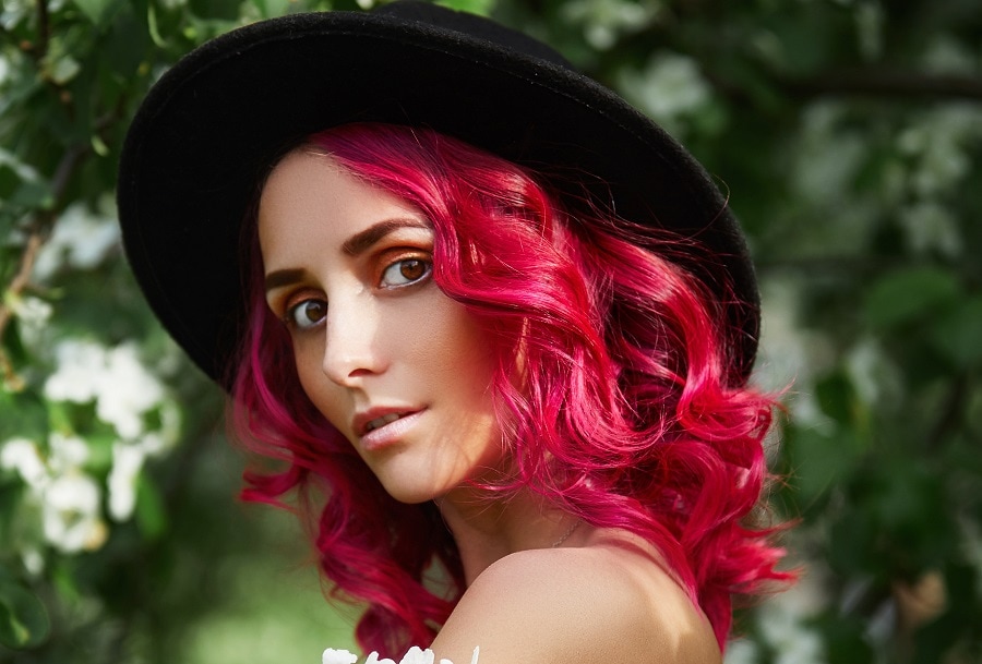 medium curly pink hairstyle for women with heart face