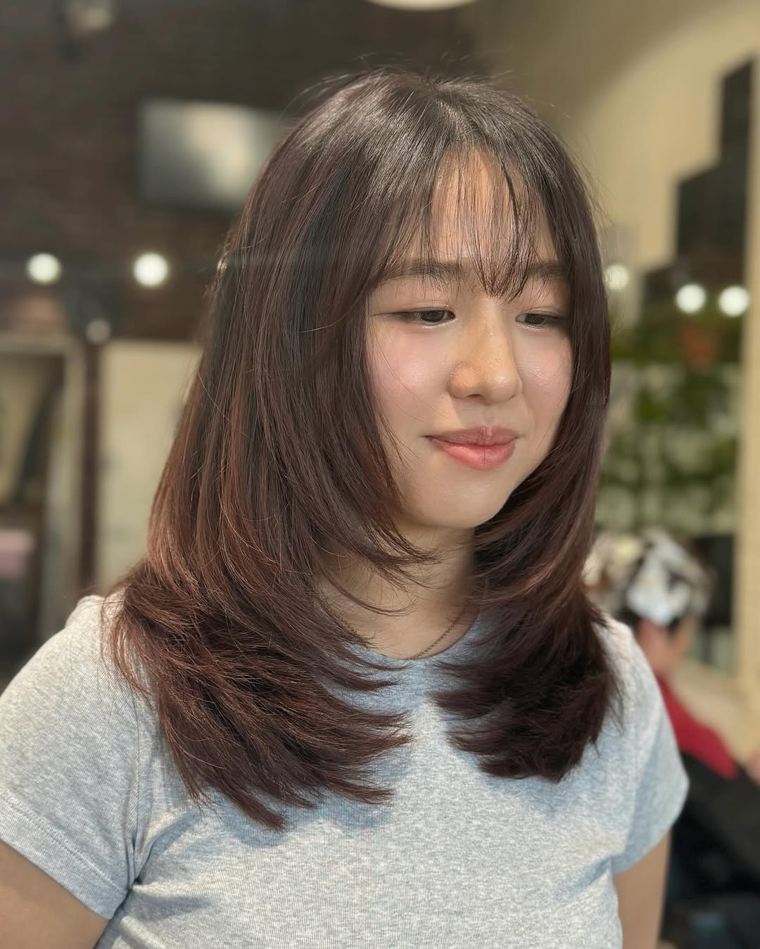 medium length haircut with face framing layers and wispy bangs