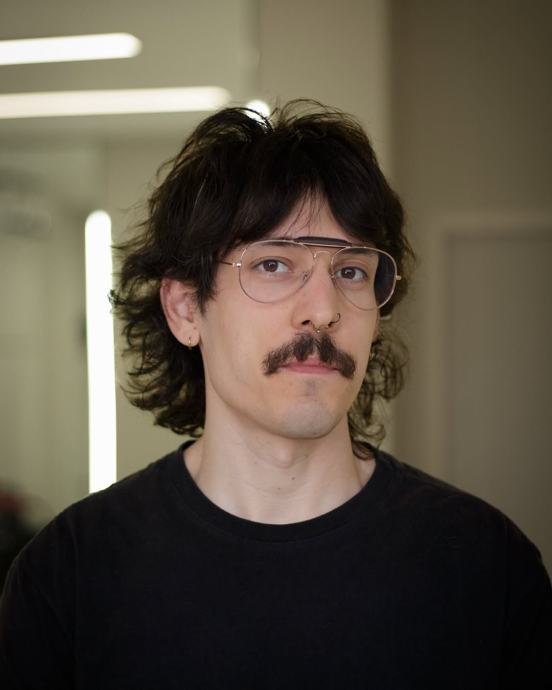 Man with dark brown wavy shaggy haircut featuring full curtain bangs