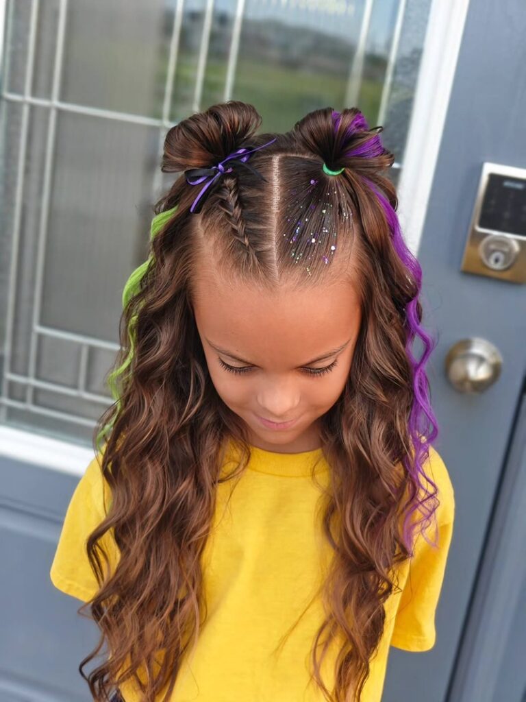 9 year old girl with a middle-parted curly hairstyle featuring space buns, colorful extensions, and hair glitter