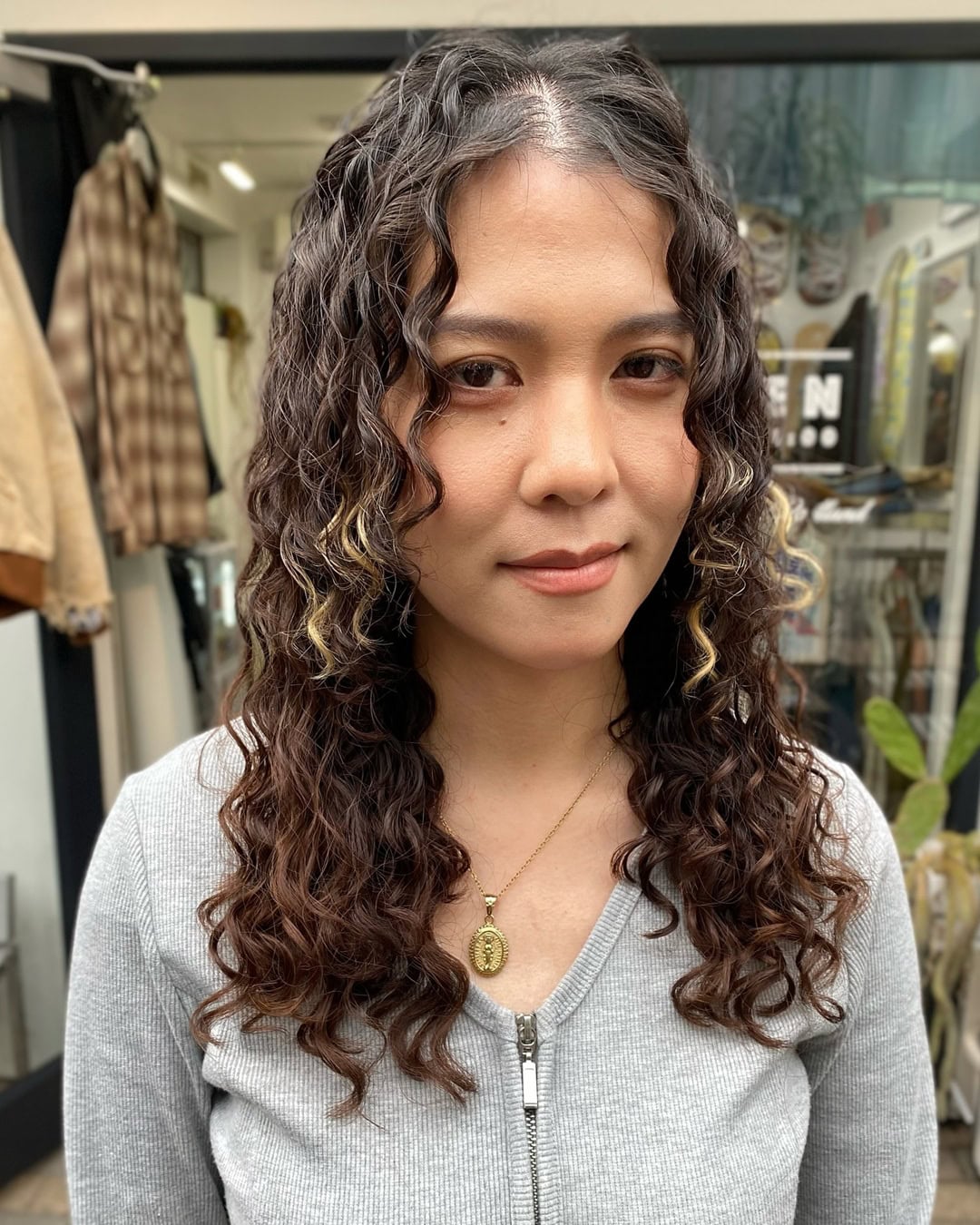 middle parted dark curly perm and blonde highlights