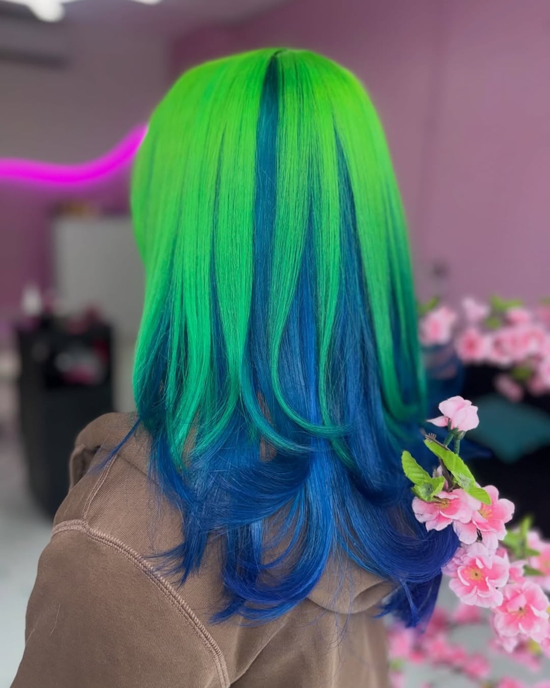 Back view of long hair featuring neon green top layers and deep blue peekaboo highlights