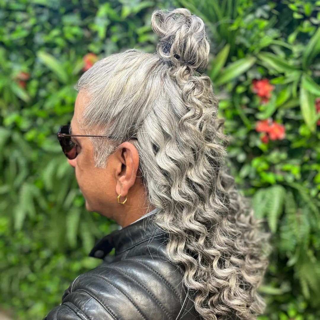 Older man with long curly silver hair styled in a half-up high bun