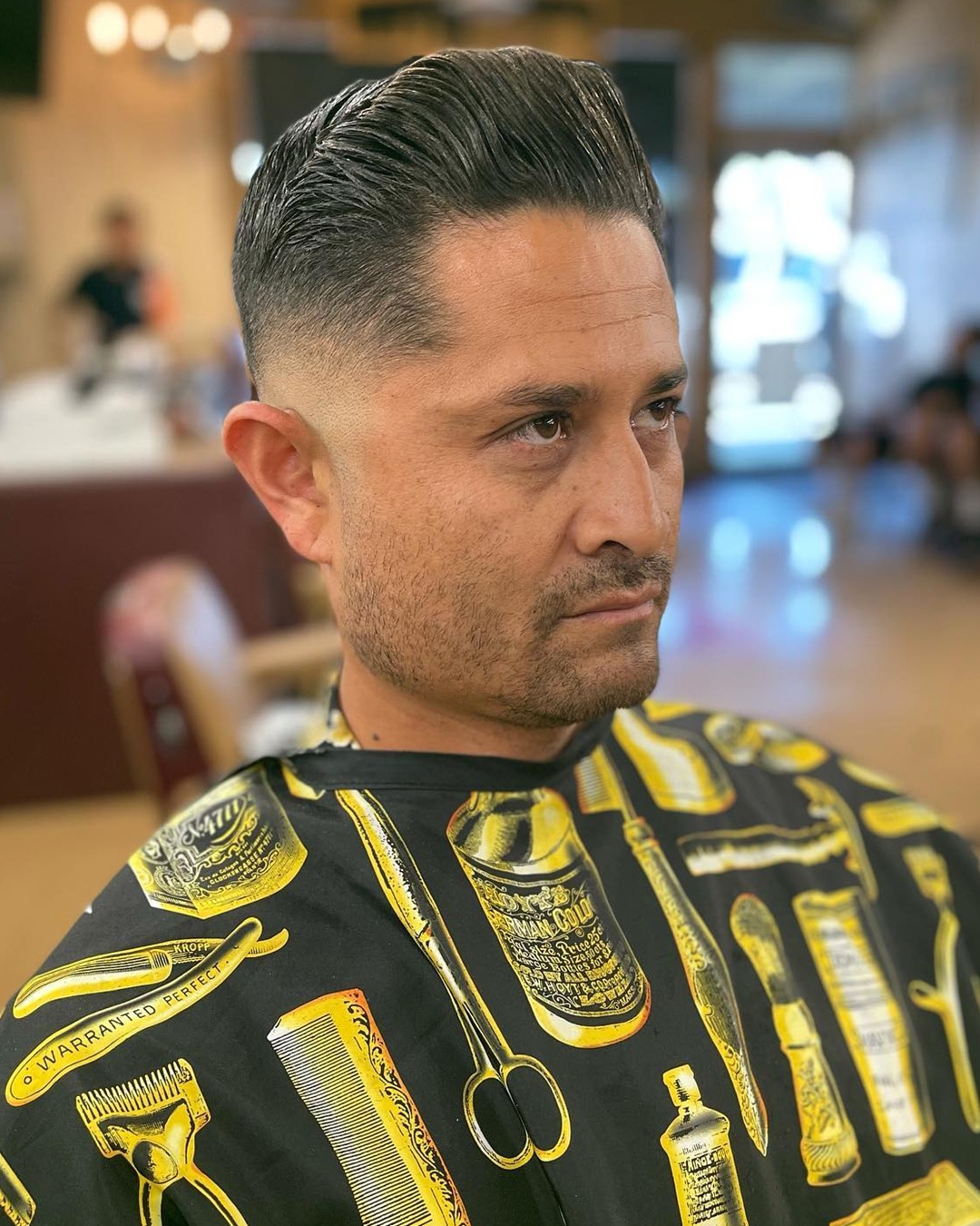 Man with a mid skin fade and high-volume pompadour comb over combed back smoothly.