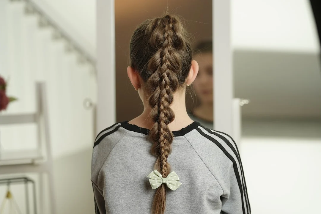 Pull through braid tutorial: back view of a stacked pull-through braid ponytail finished with a green polka-dot bow