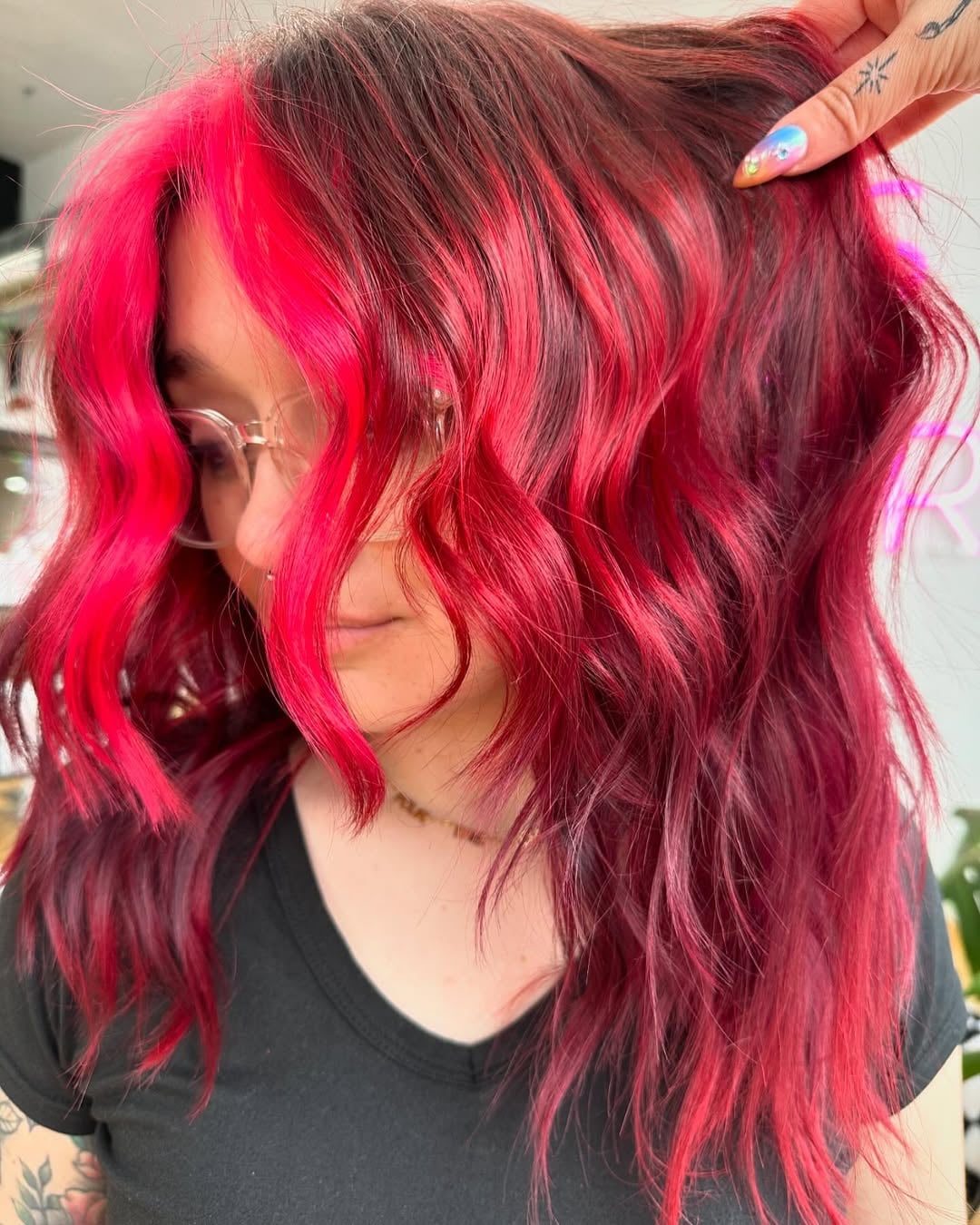 Woman with textured red wine hair color featuring a bright pink face-framing money piece
