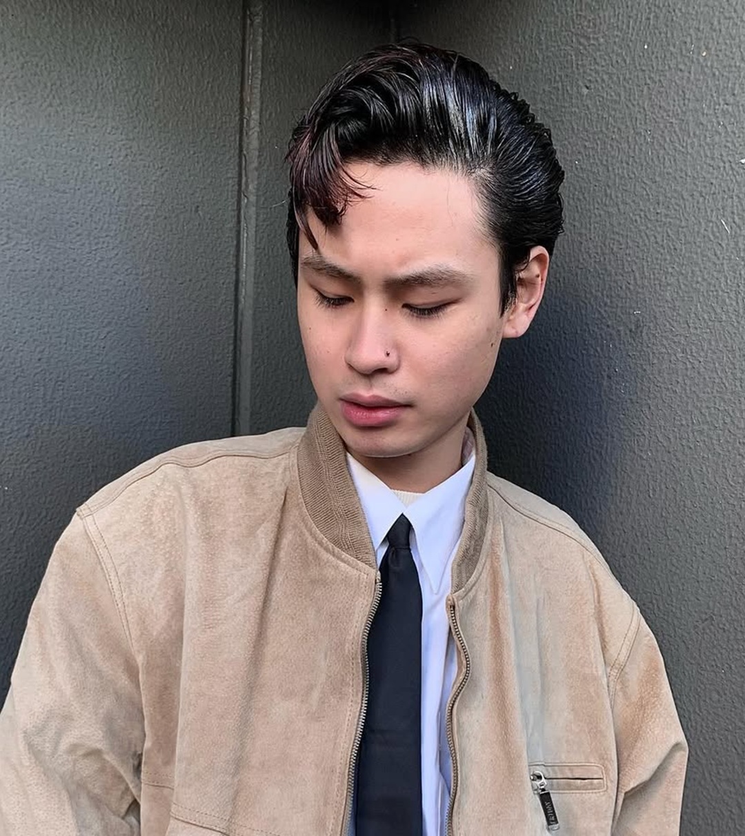 High-shine black messy pompadour and a stray fringe strand