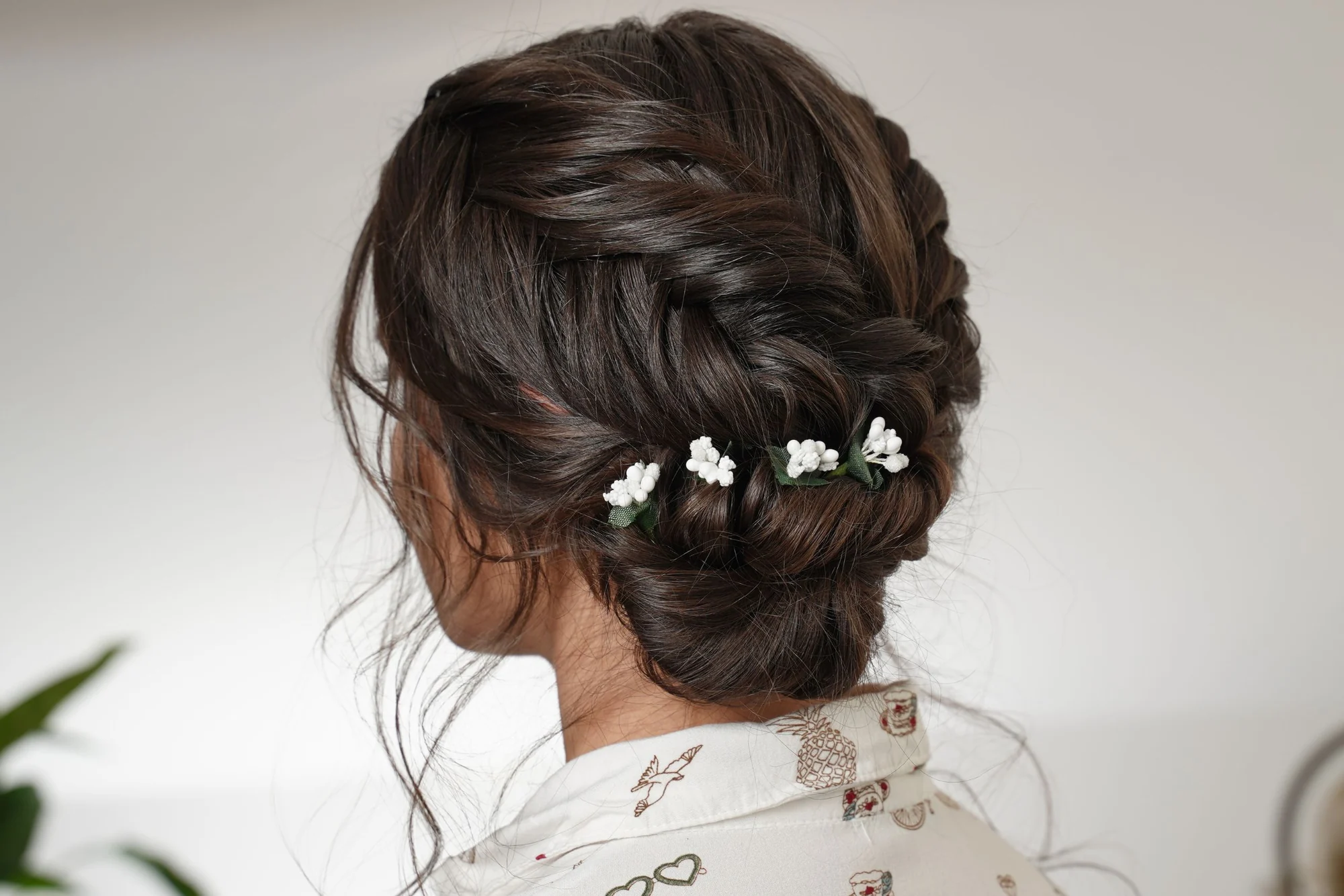 Reverse fishtail braid with bun tutorial: back view of the finished low bun trimmed with baby&rsquo;s breath flowers