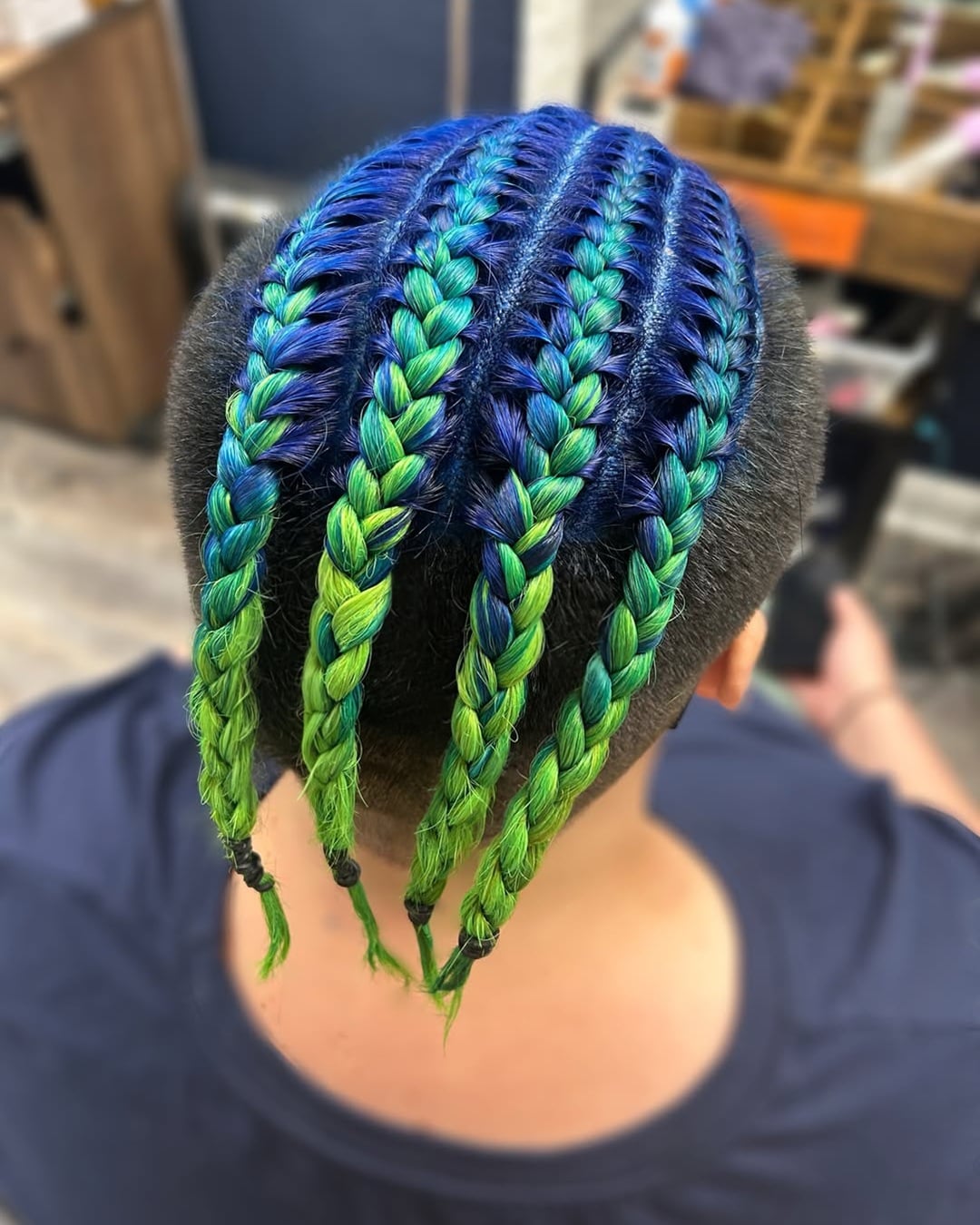 Braided cornrows with a royal blue to lime green hair color gradient and an undercut