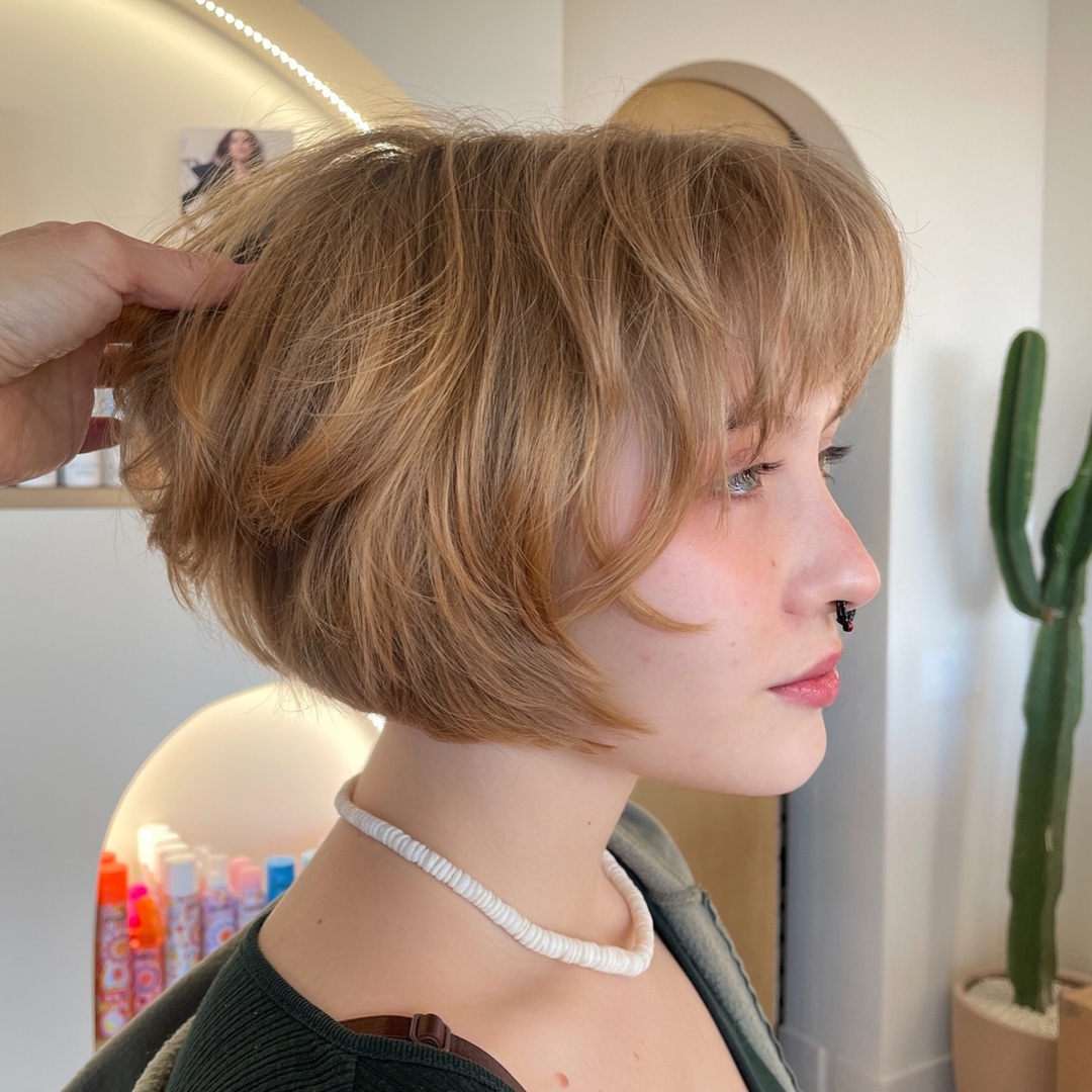 honey blonde layered short bob haircut and wispy bangs