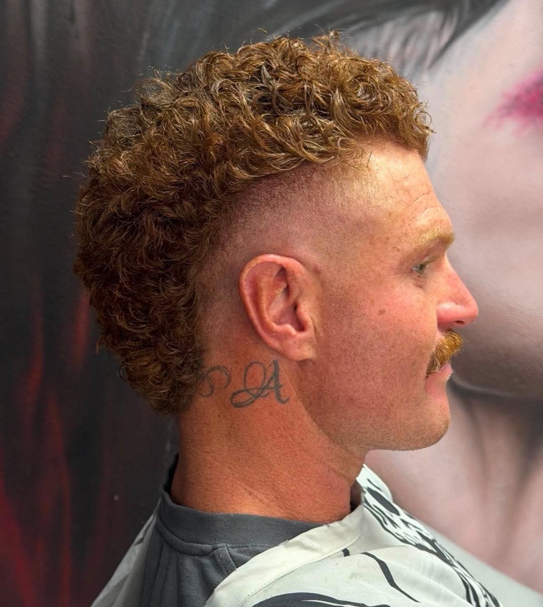 man with short curly ginger hair styled in a burst fade mullet