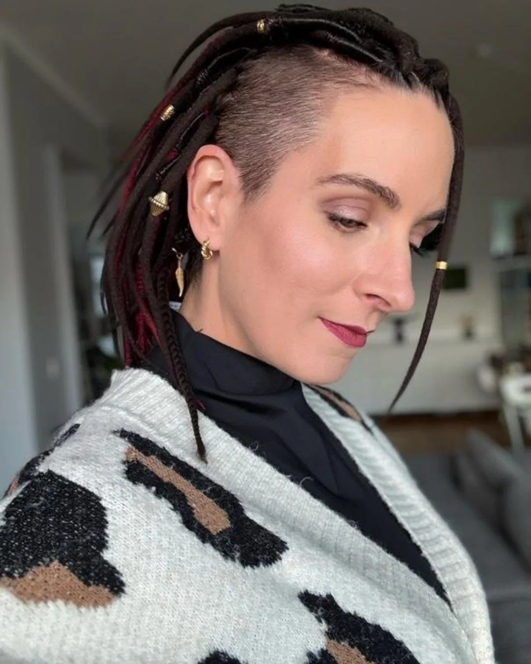 Side-swept short dreadlocks featuring a shaved side undercut and metallic gold cuffs