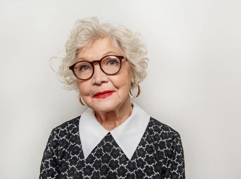 short curly hairstyle for over 50 with glasses