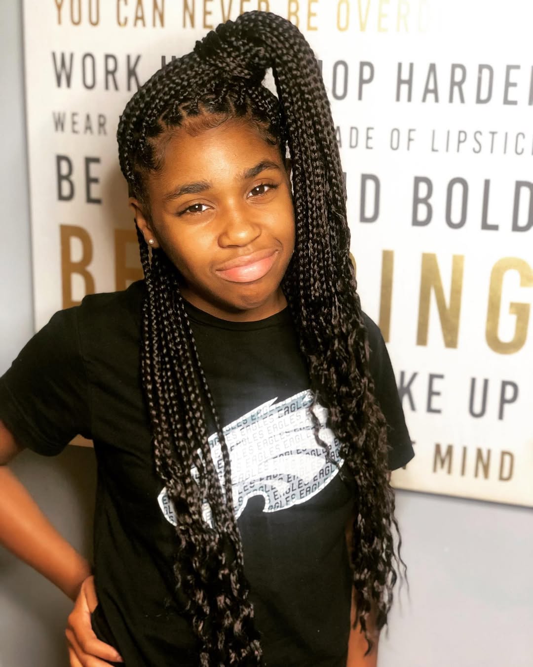 Little black girl styled in a high side ponytail with long box braids and curly ends