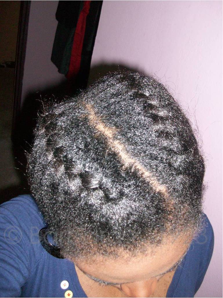 Two French braids on textured hair, divided by a slanted side part.