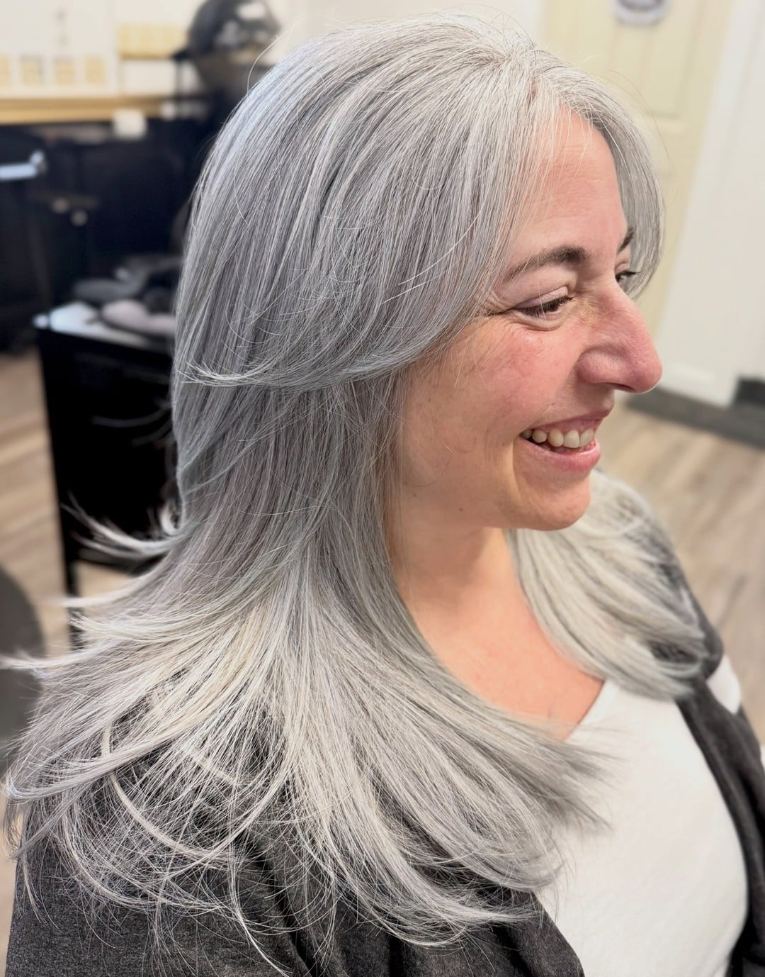 Older woman with long silver-gray hair and feathered layers, face-framing sections
