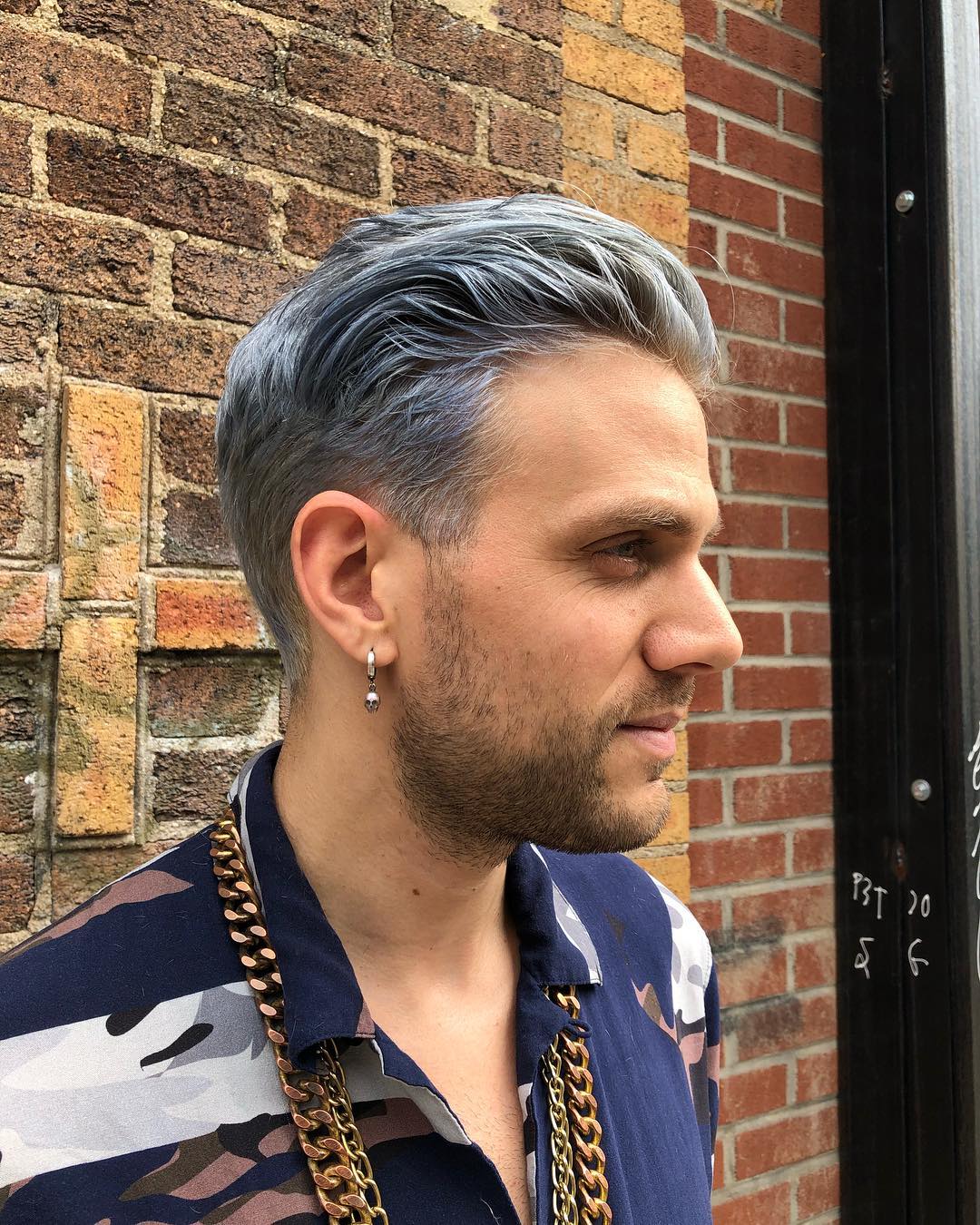 Side profile of a man with a silver grey messy pompadour hairstyle