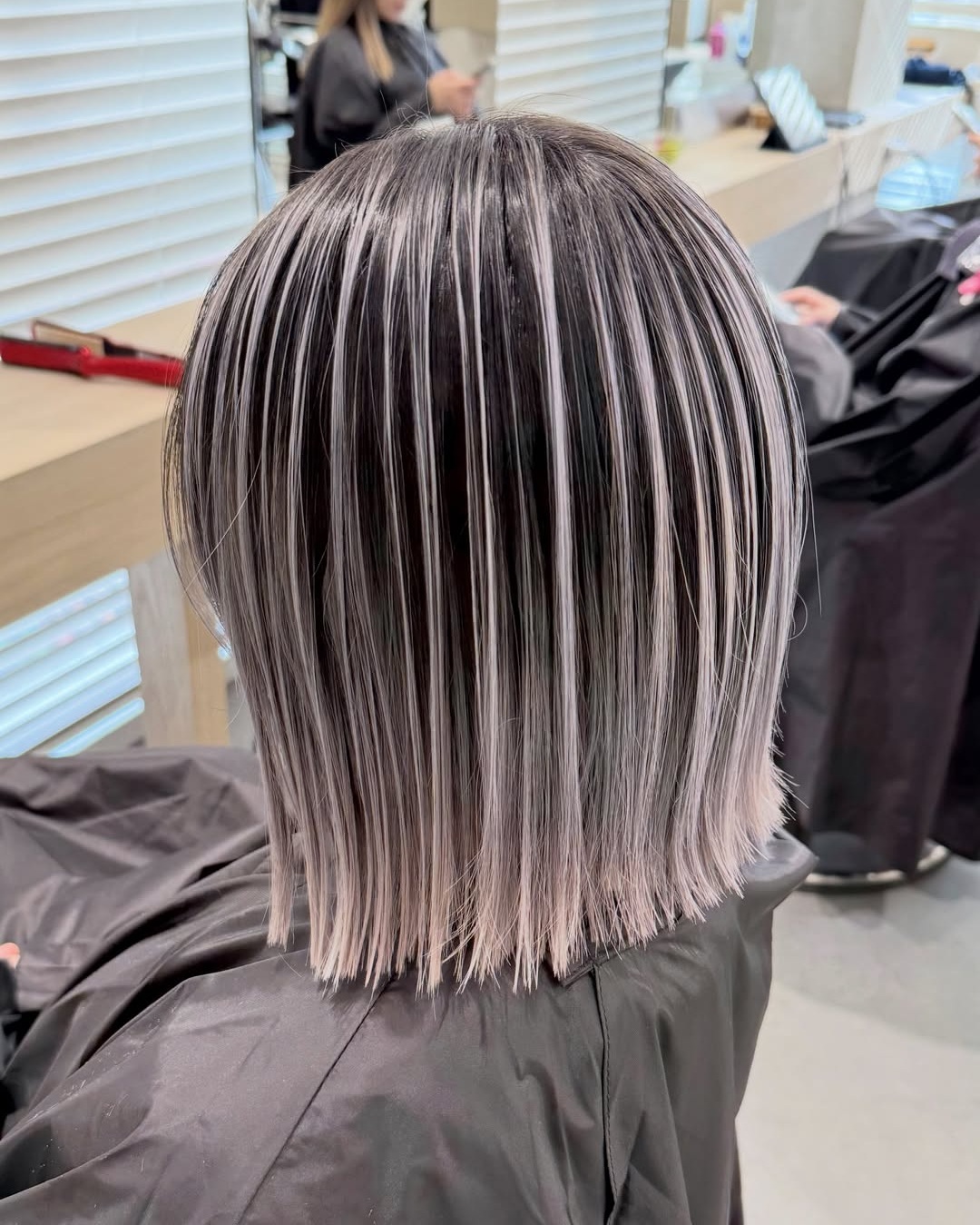 Back view of a sleek blunt bob with fine weave silver highlights