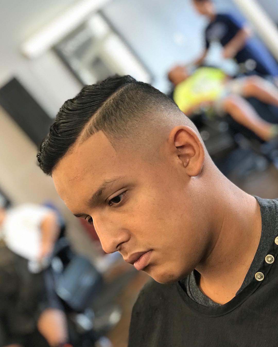 Man with a high skin fade, razor-shaved hard part, and crisp temple line-up