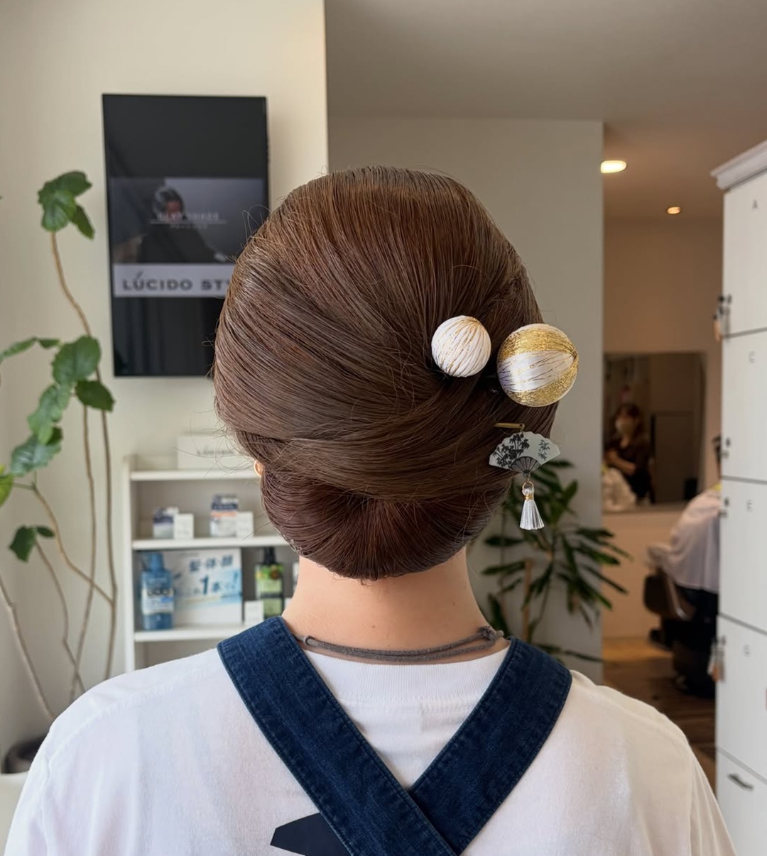 Sleek low rolled Japanese hair bun styled with traditional white and gold kanzashi ornaments